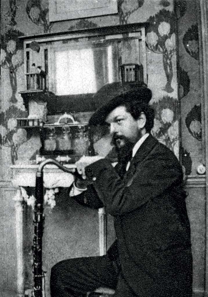 Photograph of Claude Debussy posed with his hands resting on top of a bassoon