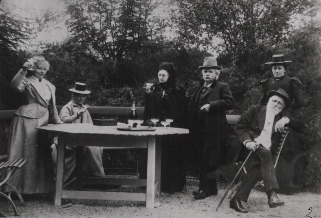 Edvard Grieg and his friends sitting outside at a table