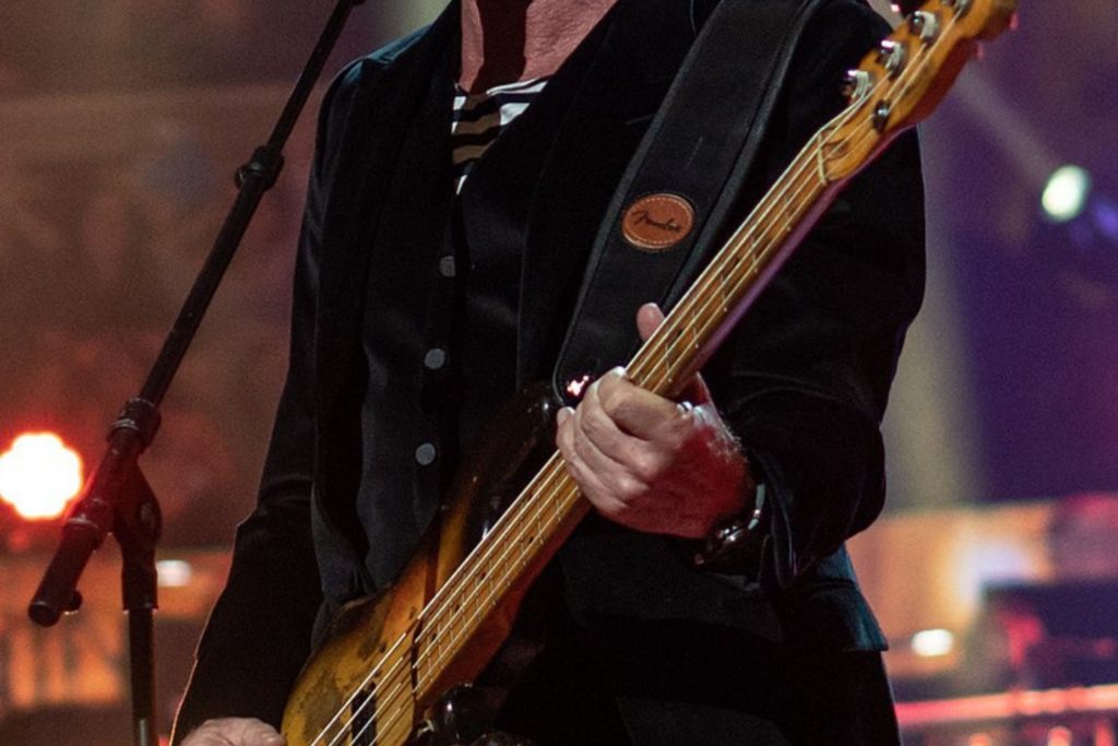 Singer Sting singing and playing guitar on stage