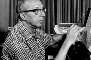 Composer Aaron Copland at the piano writing music