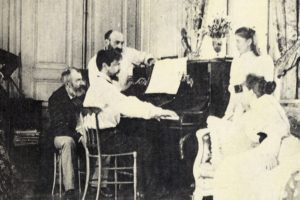 photograph of Claude Debussy playing piano while others watch on