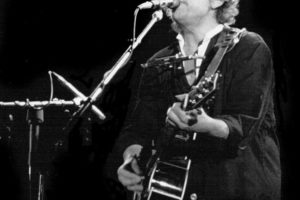 Musician Bob Dylan singing and playing guitar on stage