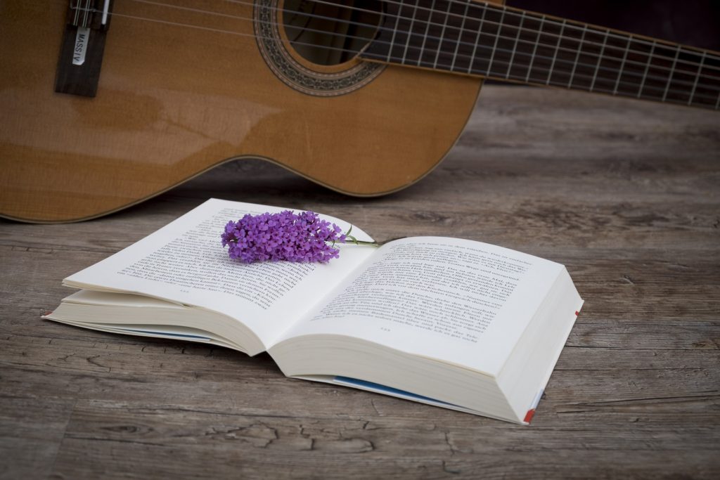 Book opened up with a guitar propped behind it