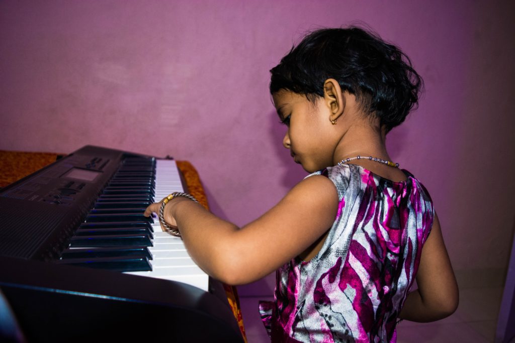 Young girl in dress playing a keyboard piano