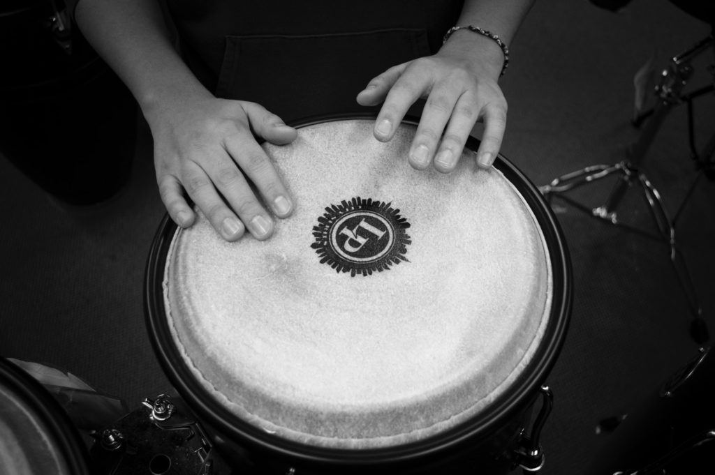 Alt Text: A black and white photo of a young person’s hands on a drum