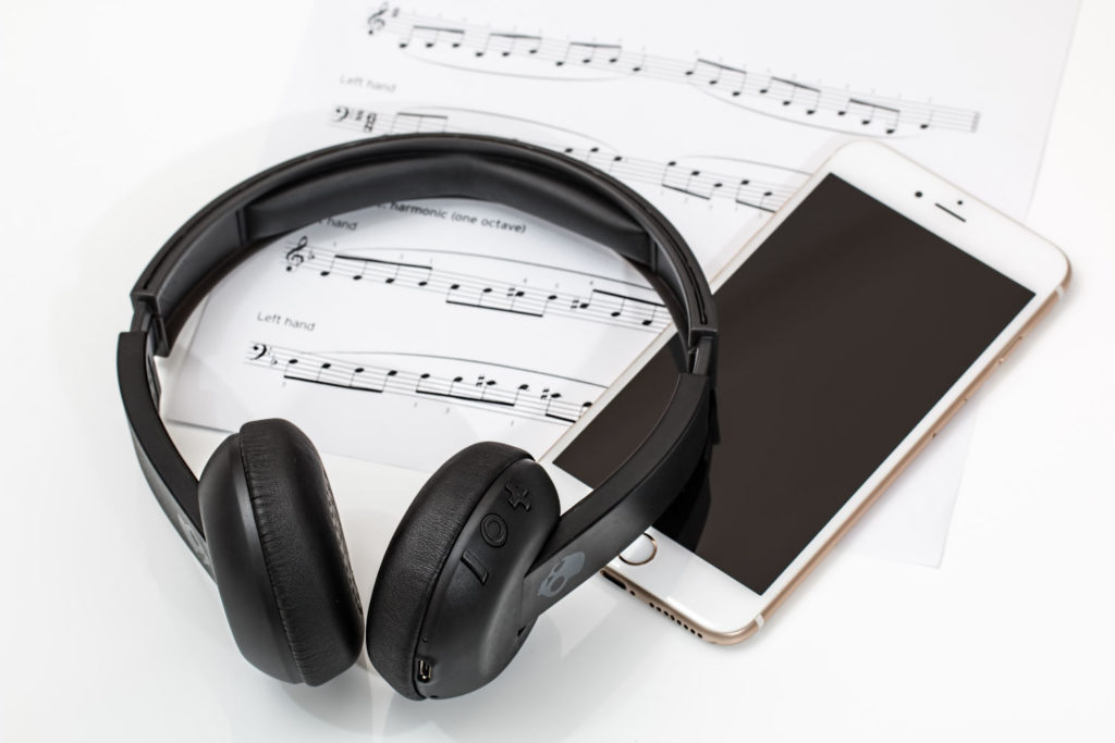 Headphones and an iphone sitting on top of sheet music