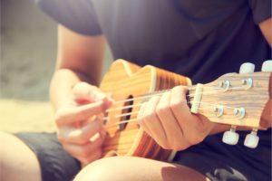 close up shot of a person playing the ukulele