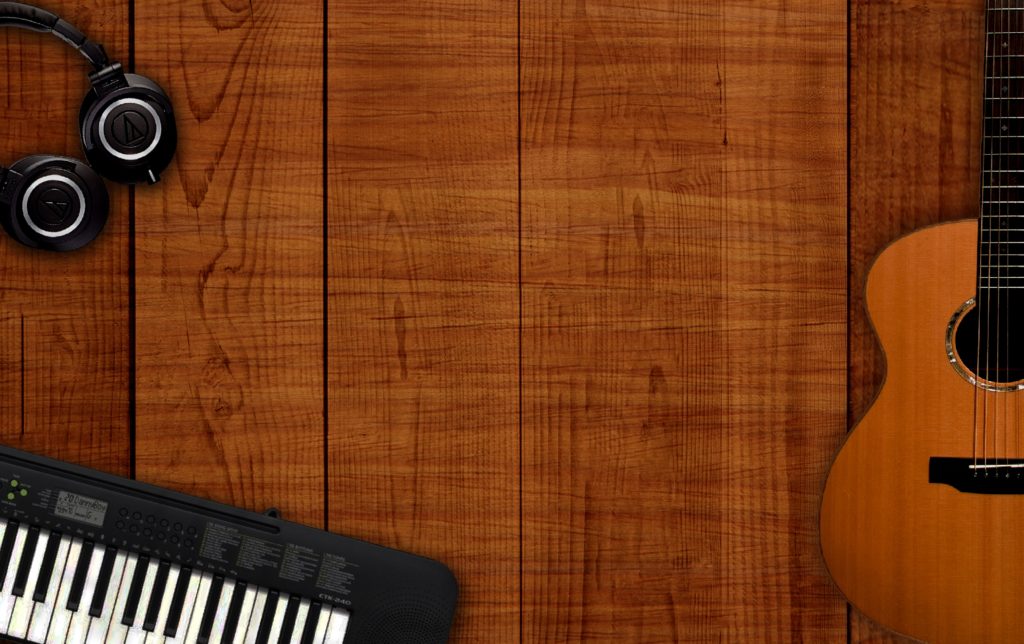 Guitar, keyboard, and headphones set on a hardwood floor